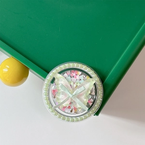Detail of a phone socket featuring a translucent butterfly with green ribbon and pearls