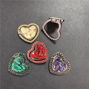 Macro view of heart-shaped metal phone ring holders with glittering rhinestones