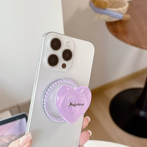 Close-up of heart-shaped purple glitter phone grip with pearled base on white smartphone