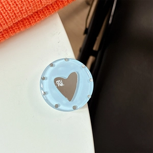 Close-up of heart mirror phone grip on light blue translucent acrylic base
