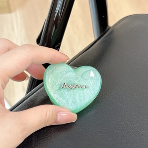 Detail of heart-shaped mint green magnetic phone stand with silver glitter and logo