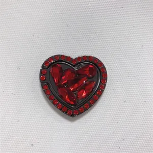 Macro detail of heart-shaped phone ring holder with red rhinestones and black alloy base