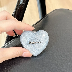 Detail of blue heart-shaped MagSafe phone grip with silver glitter and luckyhorse text