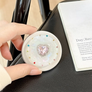 Detailed macro view of heart-shaped pink gem and pearl shell texture phone socket grip