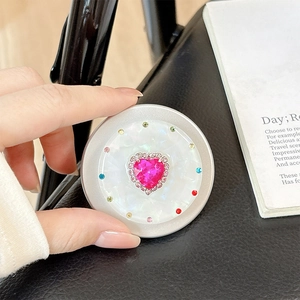 Close-up of a magnetic telescopic phone grip with a pink heart gemstone and rhinestones