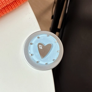 Macro detail of heart-shaped magnetic phone grip with mine text on blue polka dot base