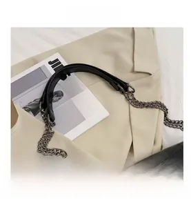 Detailed macro view of the gunmetal double-chain strap on a black leather messenger bag