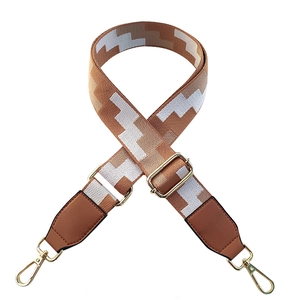 Adjustable wide replacement bag strap with brown and white geometric patterns and gold clips