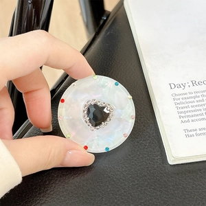 Close-up of magnetic telescopic phone grip featuring a black heart gem with rhinestones