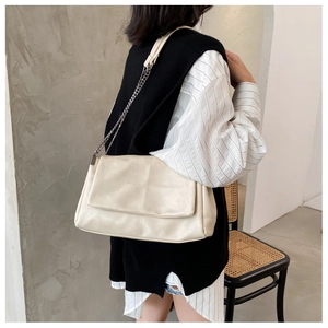 Detail of a minimalist cream PU leather crossbody bag with chain strap and stitch pattern