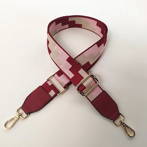 Close-up of adjustable jacquard bag strap with red geometric pattern and gold buckles