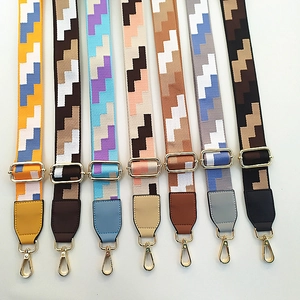 Row of colorful wide replacement bag straps with gold hardware and geometric patterns