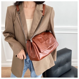Detail view of brown PU leather crossbody bag with quilted stitching on a model outfit