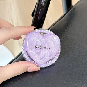 Macro detail of purple heart-shaped MagSafe phone grip with glitter and silver lettering