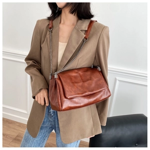 Brown retro leather messenger bag detail showing chain strap and soft texture on model