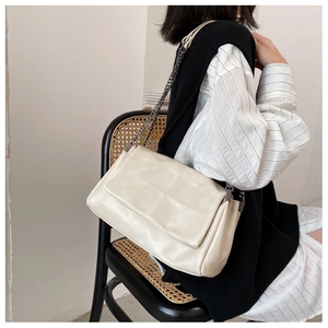 Detail of off-white quilted PU leather crossbody bag with dark grey chain strap
