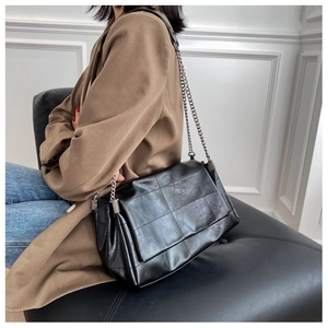 Detail of black soft PU leather shoulder bag with chic silver chain and quilted texture