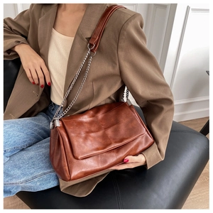 Close-up of brown PU leather shoulder bag with quilted stitching and chain strap