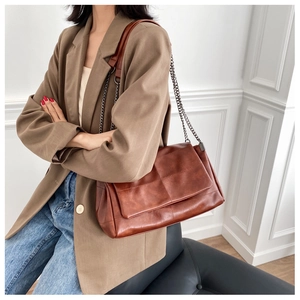 Close-up of brown PU leather shoulder bag with quilted stitching on a model side view