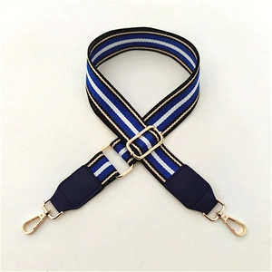 Close-up of adjustable striped bag strap with navy leather ends and gold metal hooks
