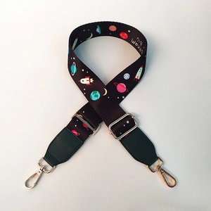Detail of adjustable bag strap with colorful space patterns and golden metal hooks