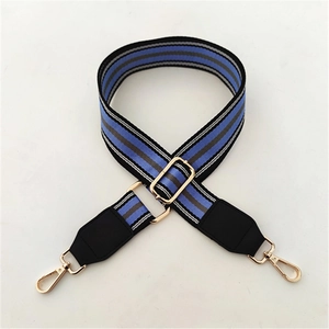 Detail of adjustable woven striped bag strap with gold metal hardware and lobster clasps