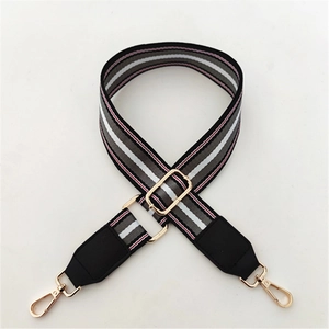 Detail of adjustable striped nylon bag strap with golden metal swivel lobster clasps