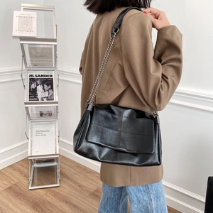 Minimalist black quilted faux leather crossbody bag with silver chain strap on model
