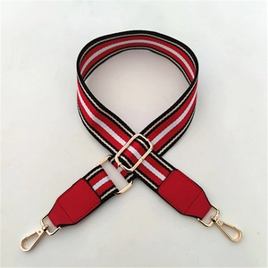 Close-up of adjustable striped wide bag strap with red leather ends and gold metal hooks