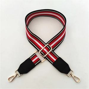 Detail of adjustable wide shoulder strap with red, white, and black stripes and gold hardware