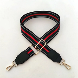 Detail of red and green striped crossbody strap with gold metal hooks and leather tips