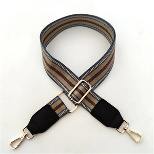 Detail of adjustable woven wide strap with striped patterns and golden metal snap hooks
