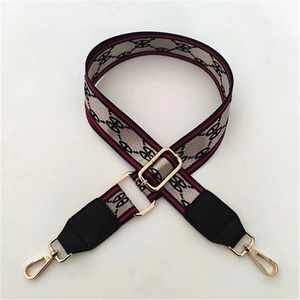 Detail of adjustable wide bag strap with striped edges and golden metal lobster clasps