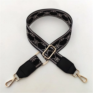 Close-up of wide woven strap with grey geometric pattern and gold-tone lobster clasps