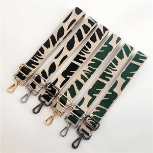 Detail of adjustable woven bag straps with tiger pattern and rotating metal lobster clasps