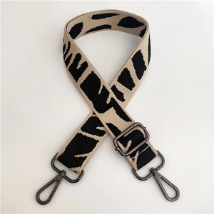 Detail of adjustable black and beige zebra pattern bag strap with gunmetal hardware