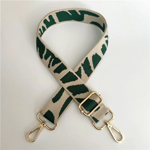 Detail of beige and green geometric jacquard webbing strap with gold metal buckles