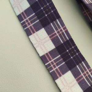 Close-up of a purple, white and pink plaid woven adjustable bag strap detail