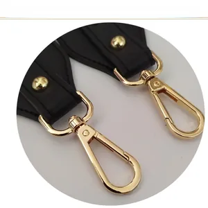 Close-up of light gold lobster clasps and black leather strap ends for shoulder bags