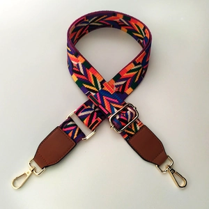 Detail of adjustable geometric patterned woven bag strap with golden metal hooks