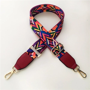 Close-up of bohemian wide bag strap with colorful geometric patterns and gold metal hooks