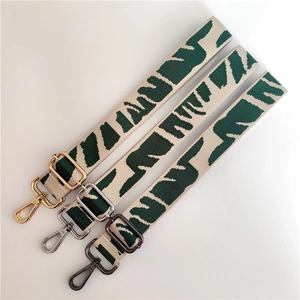 Adjustable crossbody bag strap with green jacquard webbing and three metal hardware finishes