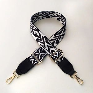 Detail of adjustable black and white geometric woven strap with gold metal swivel clasps