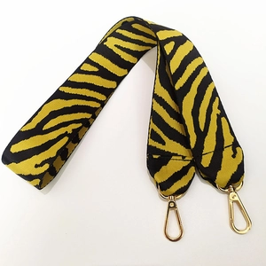 Détail d'une bandoulière large motif tigre avec mousquetons métalliques dorés