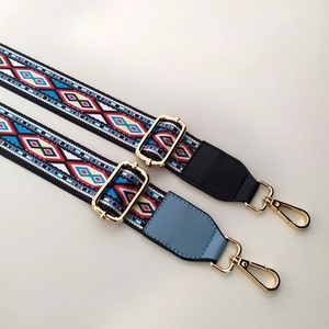 Detail of adjustable woven bag straps with ethnic geometric patterns and gold metal buckles