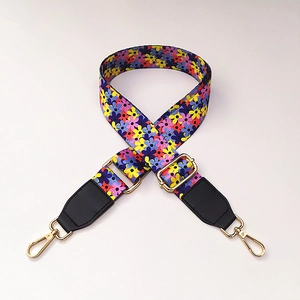 Close-up of floral wide bag strap with golden metal hooks and black leather ends
