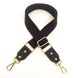 Detail of adjustable black cotton shoulder strap with gold-tone metal buckles and hooks
