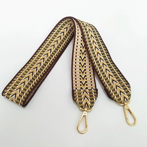Macro detail of geometric jacquard embroidered bag strap with gold lobster clasps
