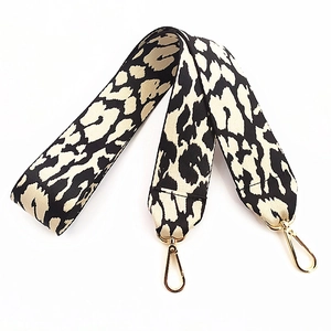 Detail of wide leopard print handbag strap with thick fabric and gold metal hooks