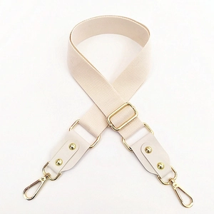 Close-up of cream cotton bag strap with golden metal buckle and lobster hooks